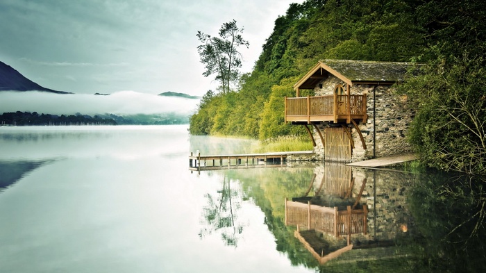 Stone boathouse on a misty lake with wooden dock