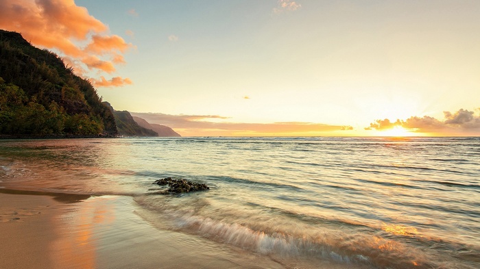 Sunset over the ocean with mountains and beach