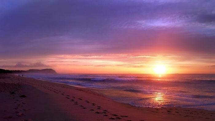 Sunset over a beach with footprints