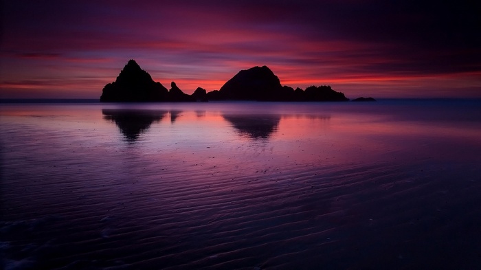 Silhouette of rock formations on a beach at sunset