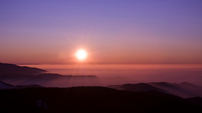 Sunrise over misty mountains with sun rays