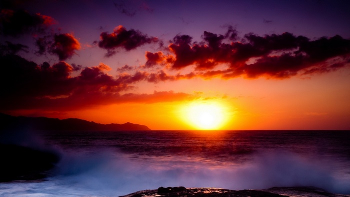 Sunset over the ocean with dramatic clouds and waves