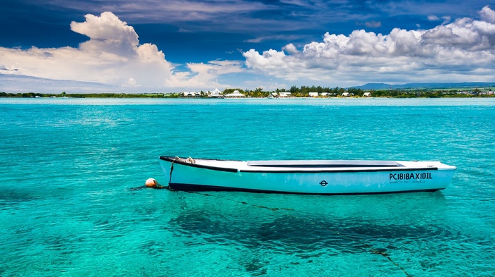 Boat on turquoise water with distant island