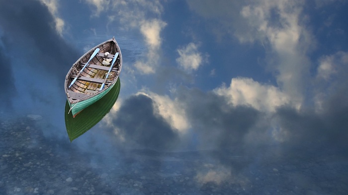 A lone rowboat floats on a reflective surface