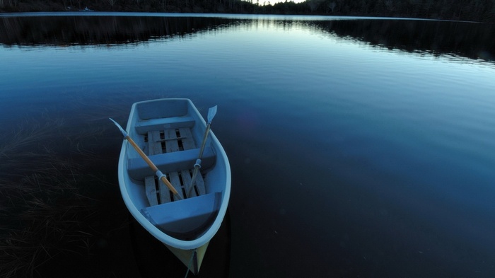 Rowboat with oars on a calm lake at dusk