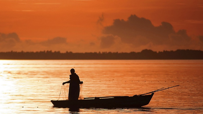 Fisherman in a boat at sunset