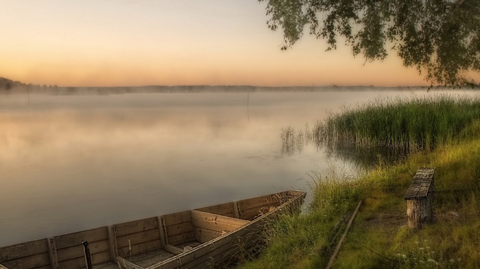 Wooden boat on a misty lake at sunrise
