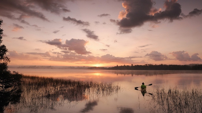 Kayaker on a misty lake at sunrise