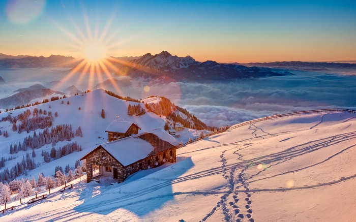 Snowy mountain cabins at sunrise with sun rays