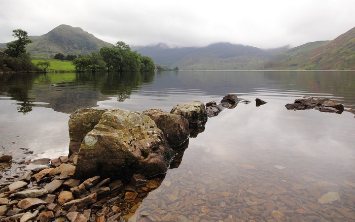Rocks in a lake with mountains in the background
