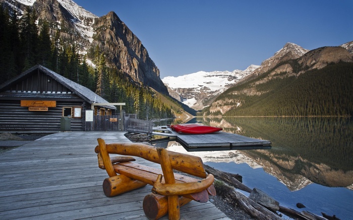 Log cabin by a lake with mountains and a red kayak