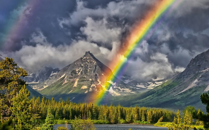 Rainbow over mountains and forest with lake