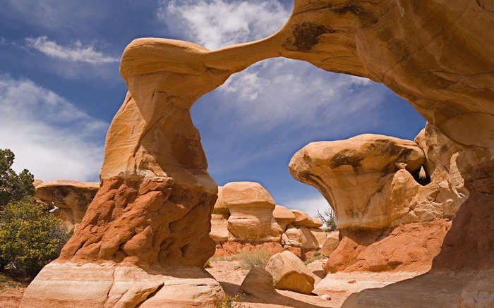 Natural sandstone arches and hoodoos under a blue sky
