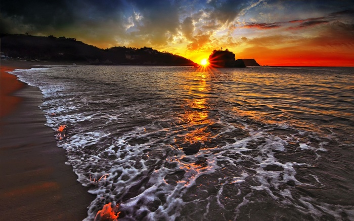 Sunset over a beach with waves crashing