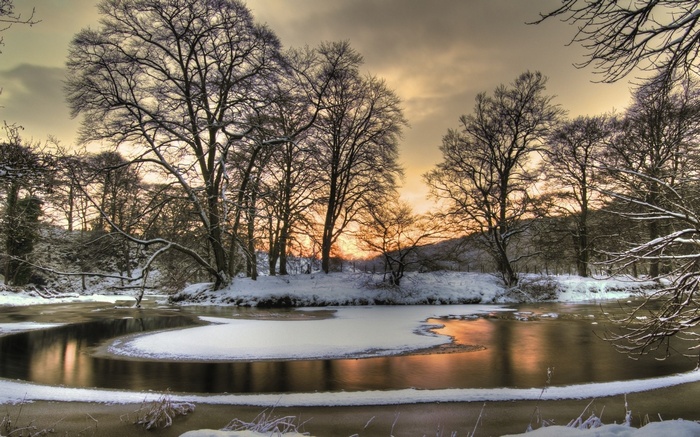 Winter river with snow-covered trees at sunset