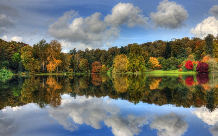 Autumn trees reflected in a lake under a cloudy sky
