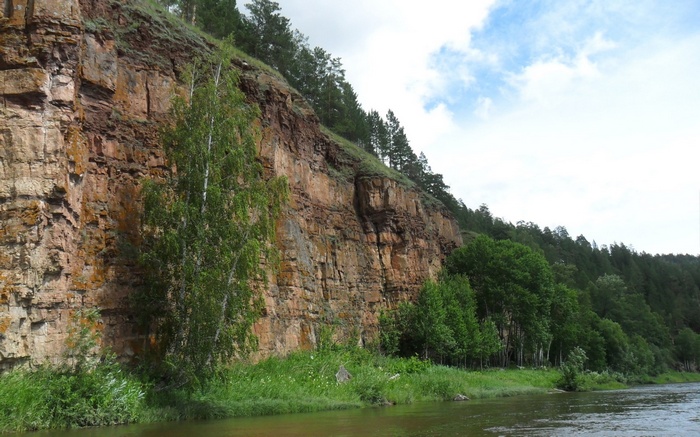 Rocky cliff face overlooking a river with trees