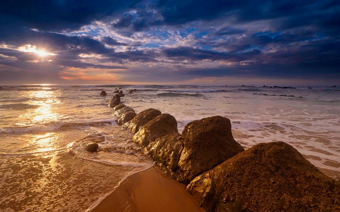 Ocean waves crash on a rocky shore at sunset