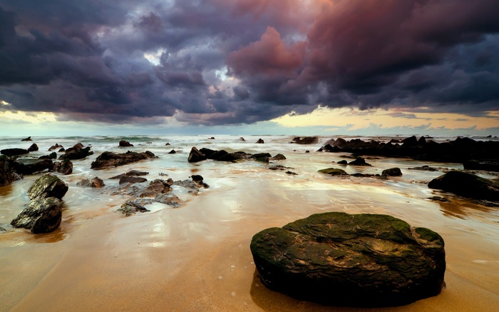 Stormy sky over rocky beach at sunset