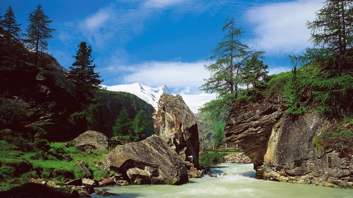 Mountain river flowing through a rocky gorge with snow-capped mountains in the background
