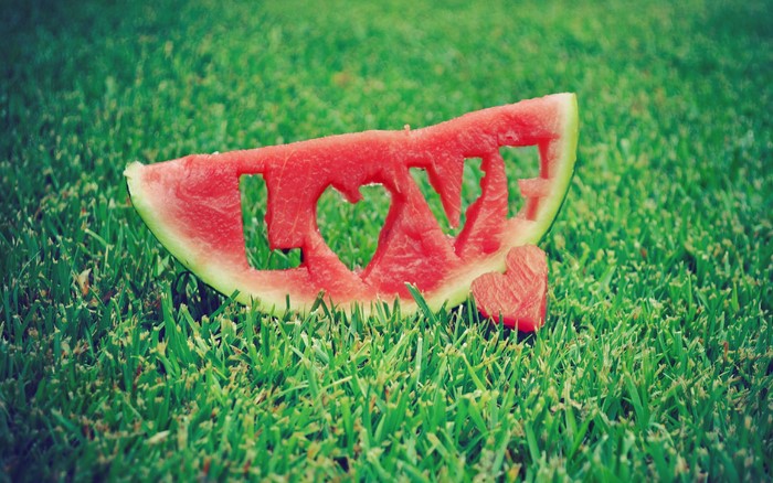 Watermelon slice with 'LOVE' carved out on grass