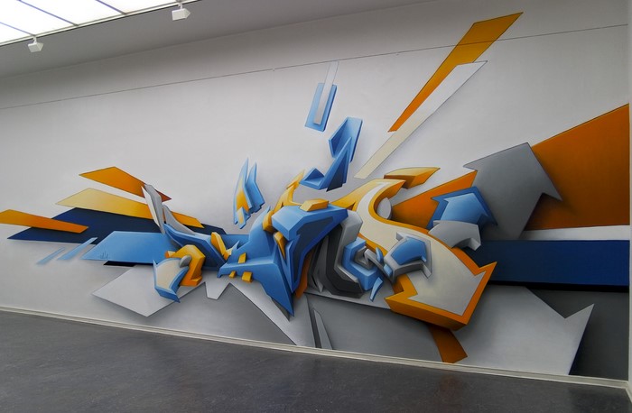 Graffiti art on a white wall with blue, orange, and gray elements