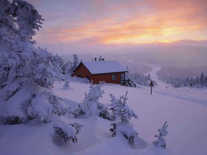 Cabin in snowy landscape at sunset
