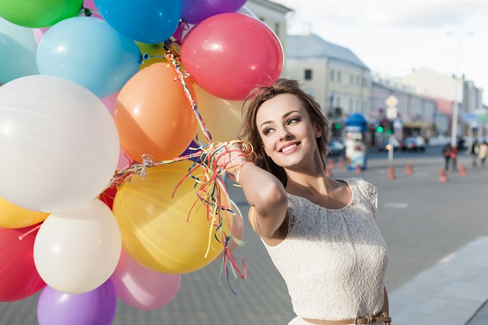 Woman holding colorful balloons on a city street