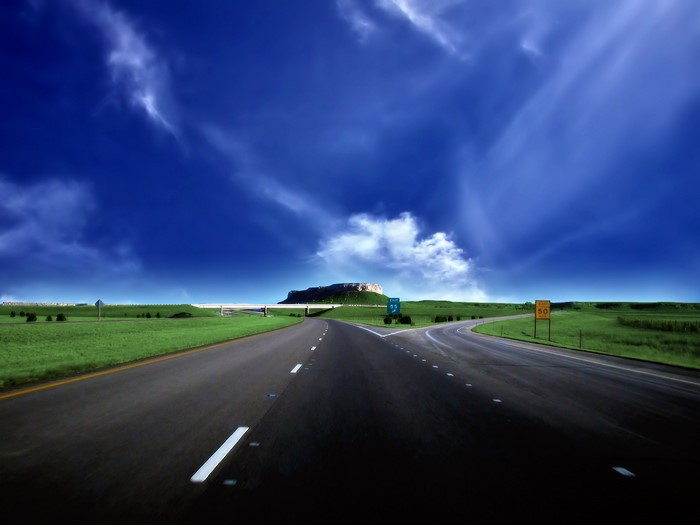 Road splitting with a mesa in the distance under a blue sky