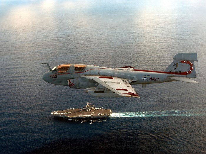 Northrop Grumman EA-6B Prowler jet flies over a Navy aircraft carrier
