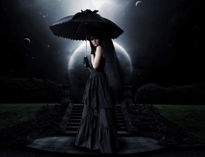Gothic woman with umbrella under moonlight
