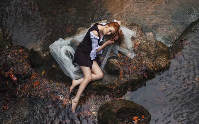 Woman lying on rocks in a stream