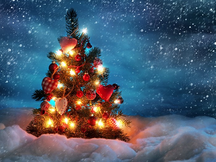 Christmas tree with lights and ornaments in snow
