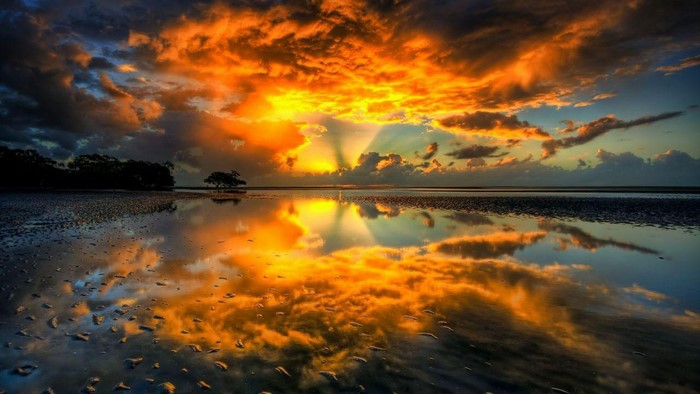 Sunset reflection on wet sand with clouds
