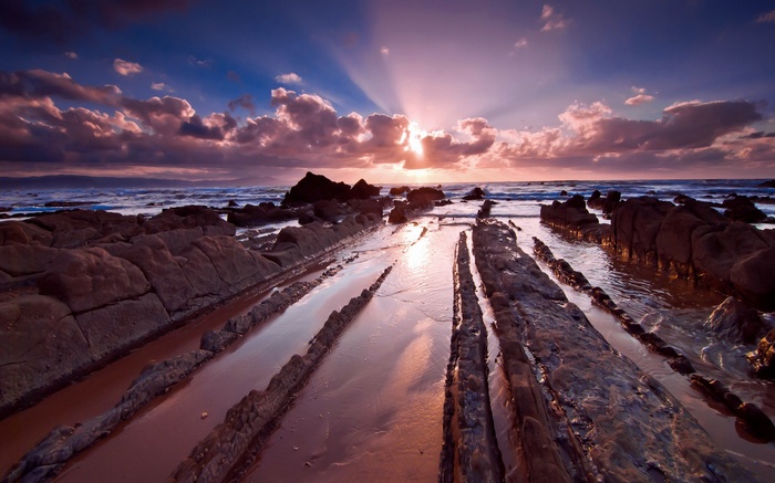 Rocky coastline at sunset with sun rays