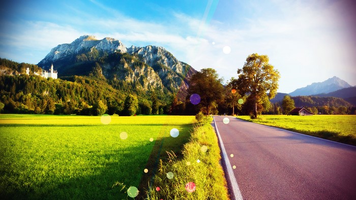 Road leading to mountains with castle and green field