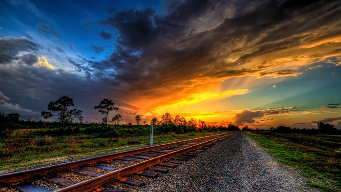 Railroad tracks at sunset with dramatic clouds