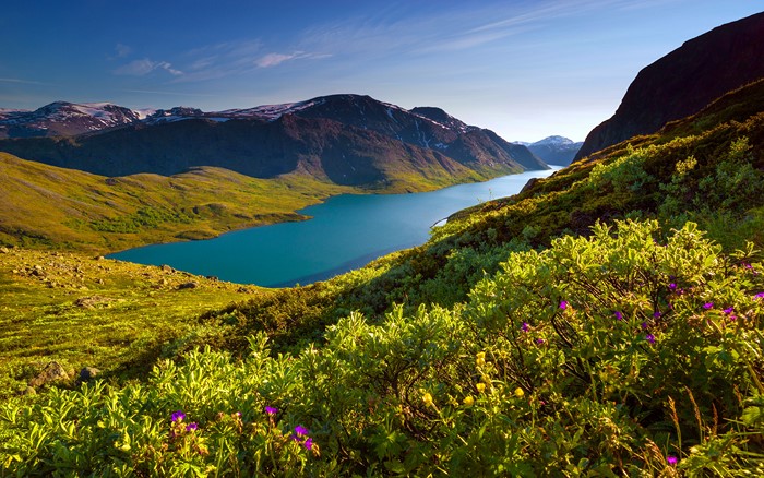 Turquoise lake surrounded by mountains and green hills