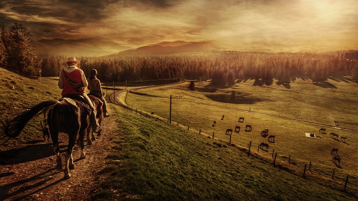 Two people on horseback in a landscape at sunset