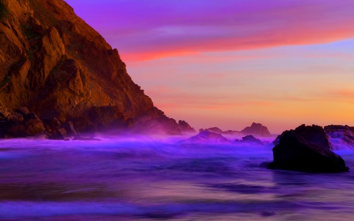 Purple Ocean Waves Crash Against Rocky Cliff at Sunset