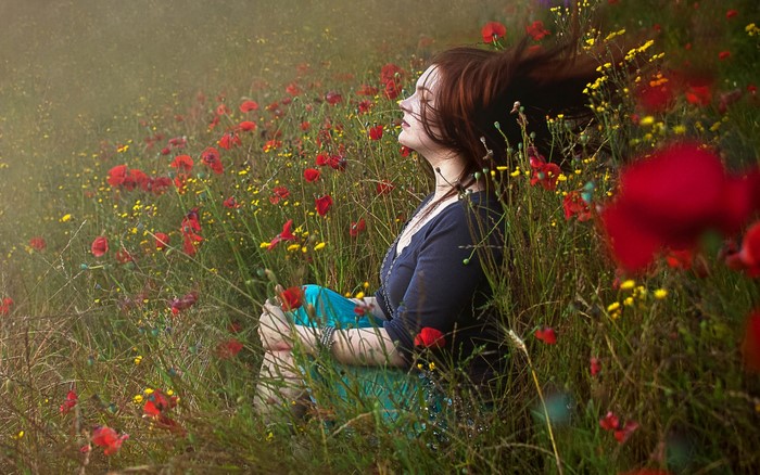 Woman sitting in a field of poppies