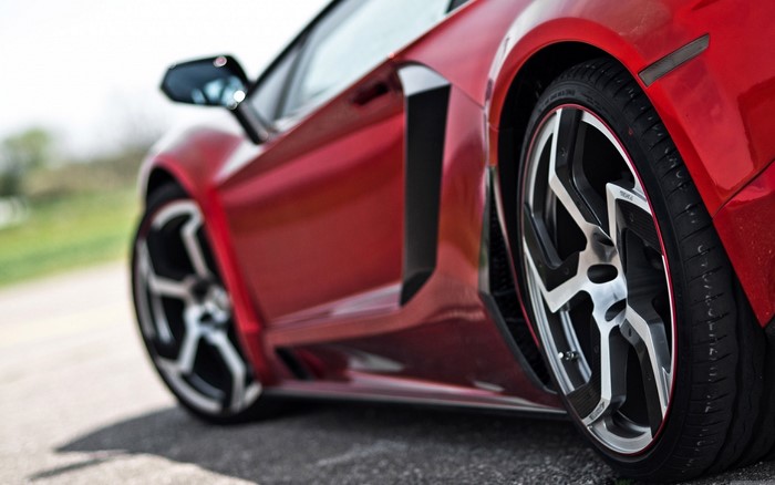 Red sports car with custom wheels on a road