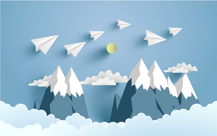 Paper planes flying over mountains and clouds
