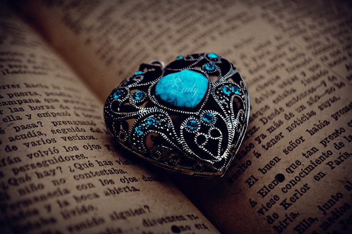 Heart-shaped locket with blue gems on an open book