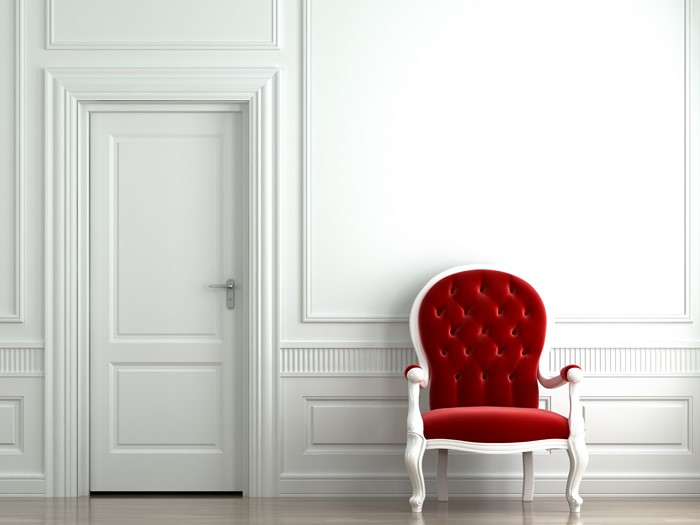 Red armchair in a white room with a white door