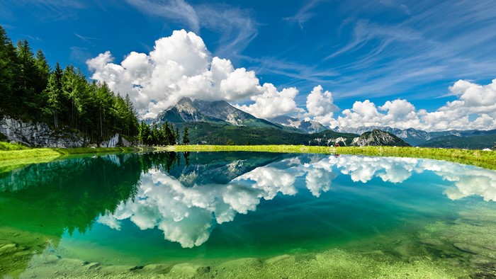 Mountain lake reflection with clouds and trees