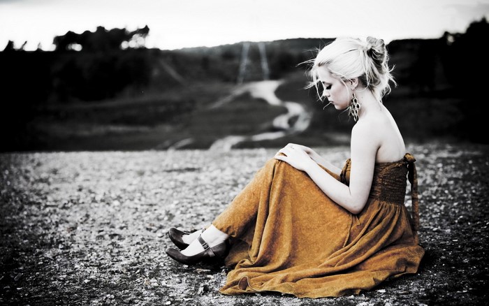 Woman in orange dress sitting on gravel