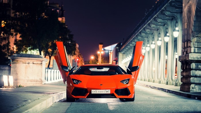 Orange Lamborghini Aventador with doors open at night