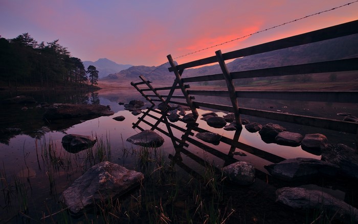 Wooden fence in a lake at sunset