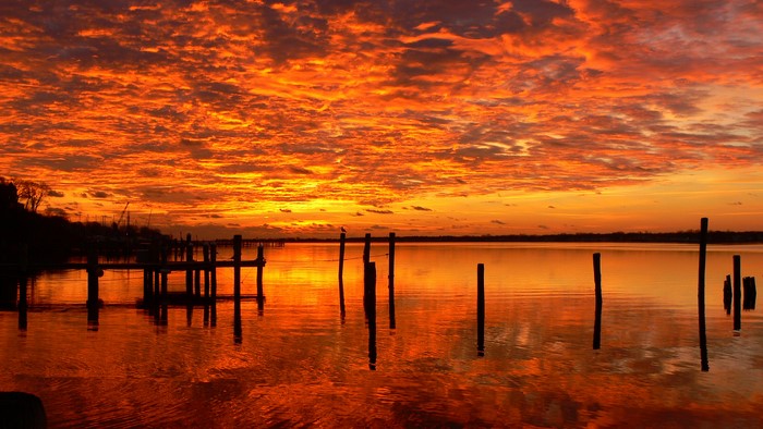 Sunset over a calm body of water with a pier